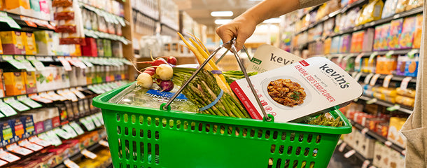 Basket filled with some groceries and a box of Kevin's General Tso's Cauliflower and Thai-Style Coconut Chicken